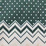 Close-up of a green knitted sweater with white geometric and zigzag patterns, perfect for holiday fashion and winter wear.
