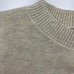 Close-up of a beige knitted sweater with a ribbed neckline and textured pattern, ideal for casual fashion and comfort.