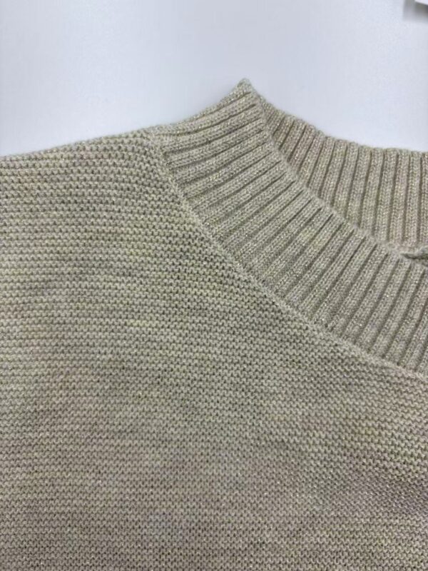 Close-up of a beige knitted sweater with a ribbed neckline and textured pattern, ideal for casual fashion and comfort.