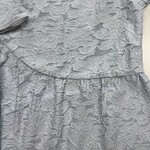 Close-up of a silver dress with intricate textured fabric, perfect for formal occasions and fashion-forward events.