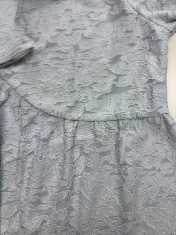 Close-up of a silver dress with intricate textured fabric, perfect for formal occasions and fashion-forward events.