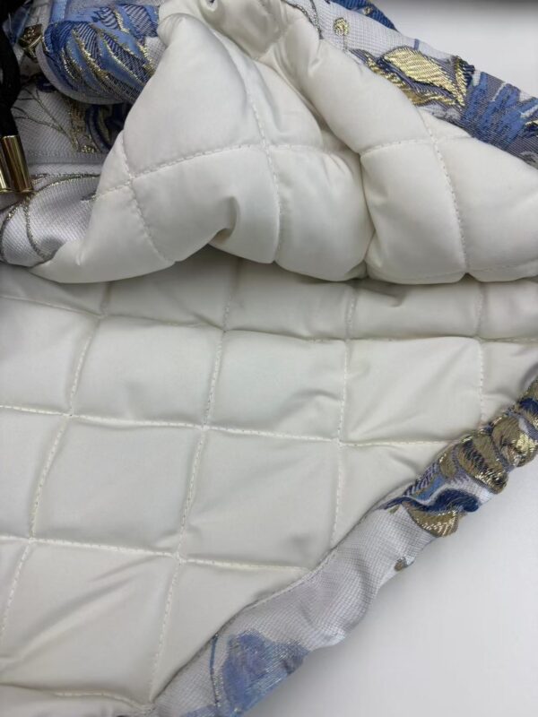 Close-up of a luxury quilted fabric with intricate embroidery and padding, showcasing high-quality craftsmanship and elegant design.