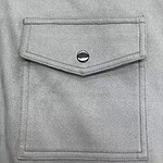 Close-up of a light grey denim jacket pocket with a silver button, showcasing casual fashion style.