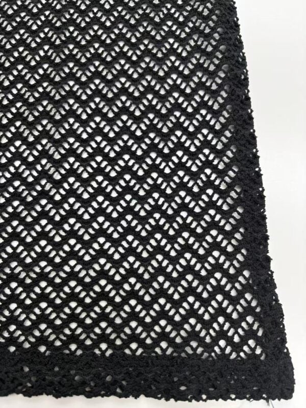 Close-up of black crochet lace fabric showcasing intricate openwork pattern, ideal for stylish clothing and accessories.
