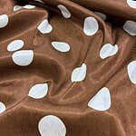 Close-up of brown fabric with white polka dots, showcasing a smooth, shiny texture suitable for clothing or accessories.