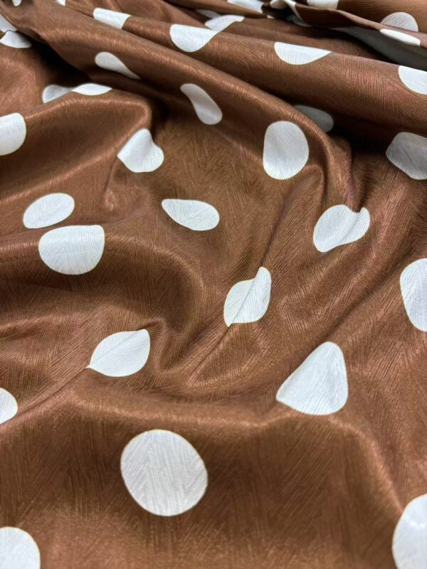 Close-up of brown fabric with white polka dots, showcasing a smooth, shiny texture suitable for clothing or accessories.