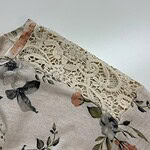 Close-up of a floral dress featuring a delicate lace trim on the shoulder, showcasing elegant fabric and intricate design for fashion and style.