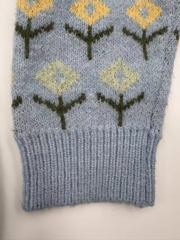Close-up of a knitted sweater featuring a geometric pattern with yellow and black diamond shapes on a light blue background.