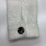 Close-up of a white wool scarf featuring a decorative black button, showcasing soft texture and stylish design for fashion accessories.