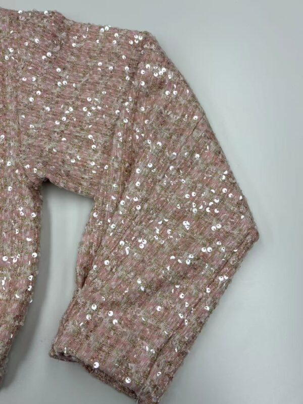Close-up of a pink blazer adorned with shiny sequins, showcasing a stylish and glamorous look for women.