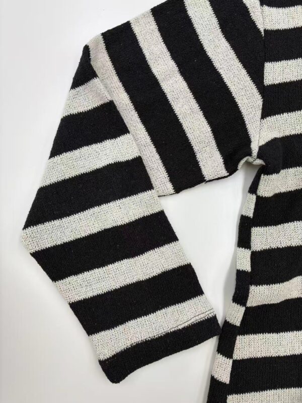 Close-up of a black and white striped sweater, showcasing the fabric texture and pattern, ideal for casual or stylish winter wear.