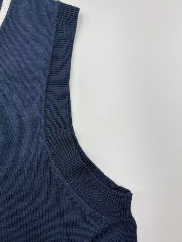 Detailed view of a navy blue knit sweater's neckline and fabric texture, showcasing high-quality craftsmanship and soft material.