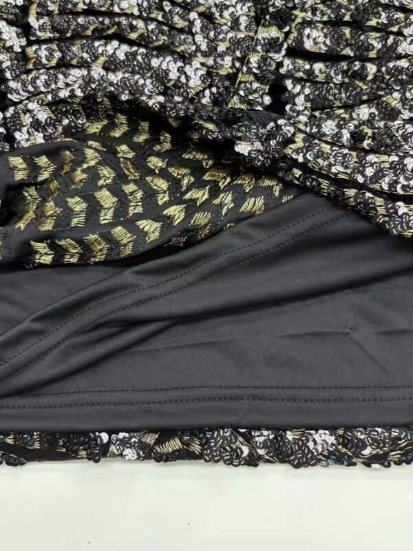 Close-up of layered fabric featuring floral, gold, and black patterns, showcasing intricate design details and textures.
