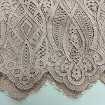 Close-up of intricate beige lace fabric with floral and geometric patterns, ideal for fashion and bridal wear.