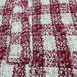 Close-up of a pink and white textured rug with a checkered pattern, featuring fluffy and looped fibers for a cozy and stylish look.