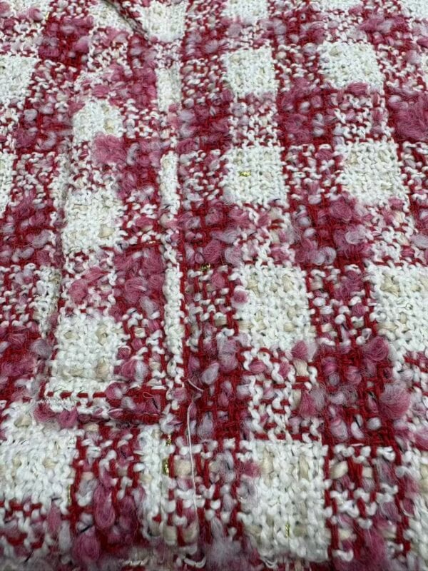 Close-up of a pink and white textured rug with a checkered pattern, featuring fluffy and looped fibers for a cozy and stylish look.