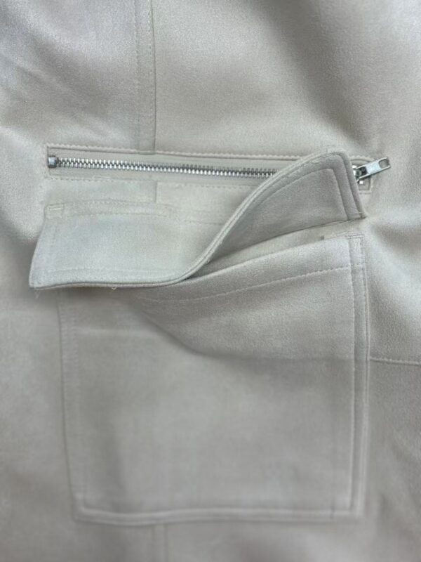 Close-up of a light grey fashion jacket featuring a zipper pocket and soft fabric texture, ideal for stylish casual wear.