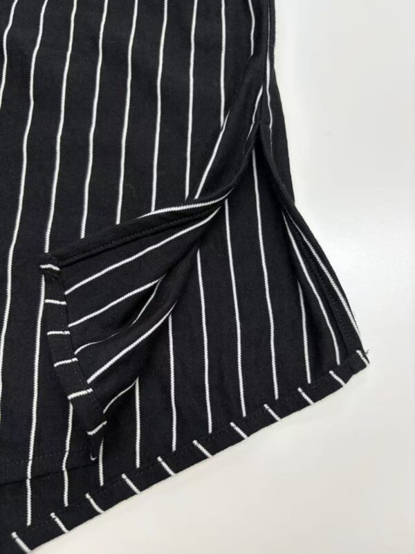 Close-up of a black skirt with white vertical pinstripes, featuring a tied knot detail and a frayed hem, suitable for fashion and style keywords.