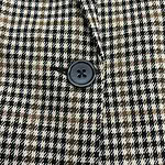 Close-up of a houndstooth patterned coat with a black button, showcasing classic fashion style and high-quality fabric suitable for stylish winter wear.