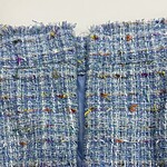 Close-up of a stylish blue tweed jacket with multicolored threads, showcasing detailed fabric texture and craftsmanship, perfect for fashion and style enthusiasts.