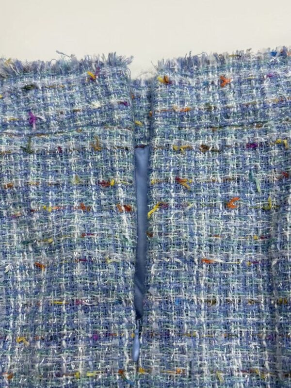 Close-up of a stylish blue tweed jacket with multicolored threads, showcasing detailed fabric texture and craftsmanship, perfect for fashion and style enthusiasts.