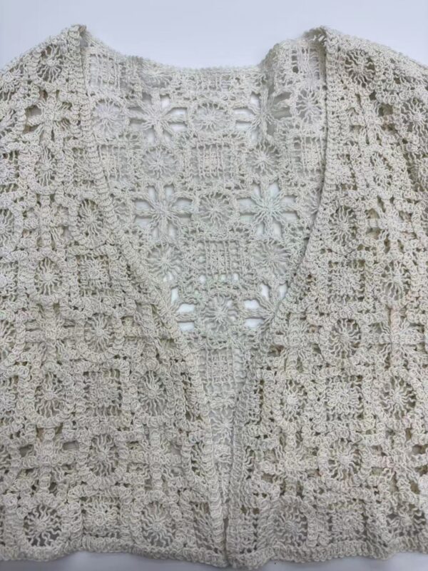 Close-up of a delicate, handcrafted crochet lace jacket in a soft cream color, showcasing intricate floral and geometric patterns, perfect for stylish summer wear.