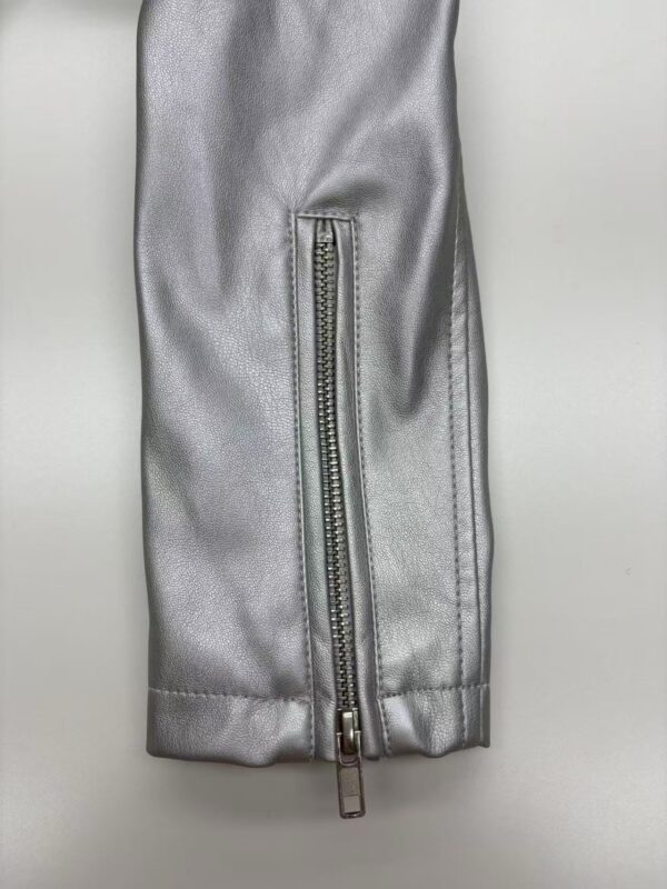 Close-up of a silver leather jacket sleeve featuring a vertical zipper, showcasing high-quality material and craftsmanship.
