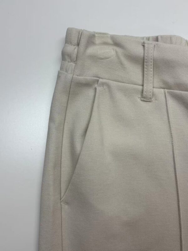 Close-up of beige men's dress pants showing waistband, belt loops, and front pocket details for a sophisticated look.