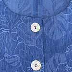 Close-up of a blue dress with a subtle floral pattern and a button-up front, showcasing a stylish and luxurious design.