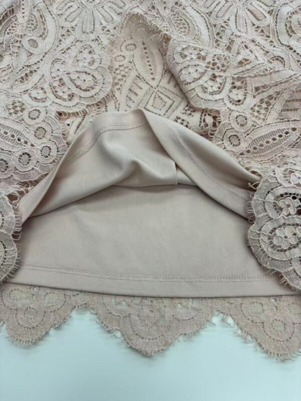 Close-up of intricate lace fabric combined with smooth beige leather, showcasing detailed craftsmanship and luxurious texture for fashion accessories or clothing.