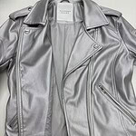 Elegant silver leather jacket with zipper details, shoulder epaulets, and classic lapel collar, perfect for fashion-forward women.
