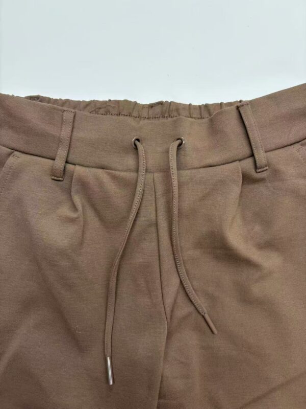 Close-up of brown casual jogger pants with elastic waistband and drawstring, suitable for comfortable everyday wear.