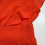Close-up of a vibrant red women's dress featuring ruffled details and a textured waistband, perfect for stylish occasions.