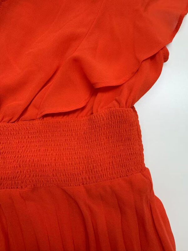 Close-up of a vibrant red women's dress featuring ruffled details and a textured waistband, perfect for stylish occasions.