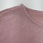 Close-up of a pink knitted sweater showing detailed stitching and fabric texture.