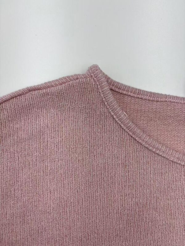 Close-up of a pink knitted sweater showing detailed stitching and fabric texture.