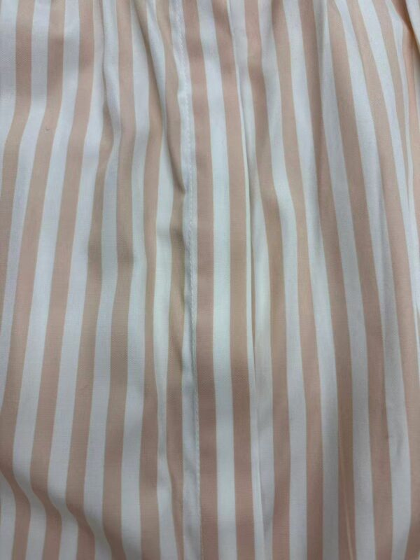 Close-up of beige and white vertical striped fabric, showing texture and stitching details.