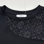Close-up of a black dress featuring a round neckline with intricate floral embroidery and sparkling embellishments for a sophisticated look.