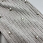 Close-up of beige fabric with vertical stripes and scattered pearl embellishments, showcasing luxury textile design.
