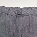 Close-up of grey men's pants with drawstring waist, suitable for casual or semi-formal wear, featuring textured fabric and modern design.