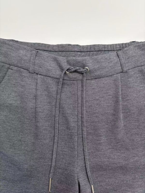 Close-up of grey men's pants with drawstring waist, suitable for casual or semi-formal wear, featuring textured fabric and modern design.