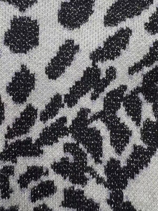 Close-up of leopard print fabric with black spots on a light background, showcasing textured material suitable for stylish clothing and accessories.
