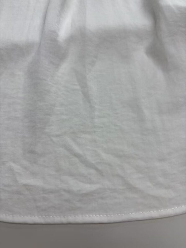 Close-up of white fabric material showing texture and slight wrinkles, ideal for fashion or textile product images.