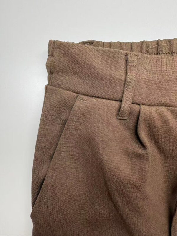 Close-up of brown casual women's pants with elastic waistband and front pocket, suitable for everyday wear and fashion.