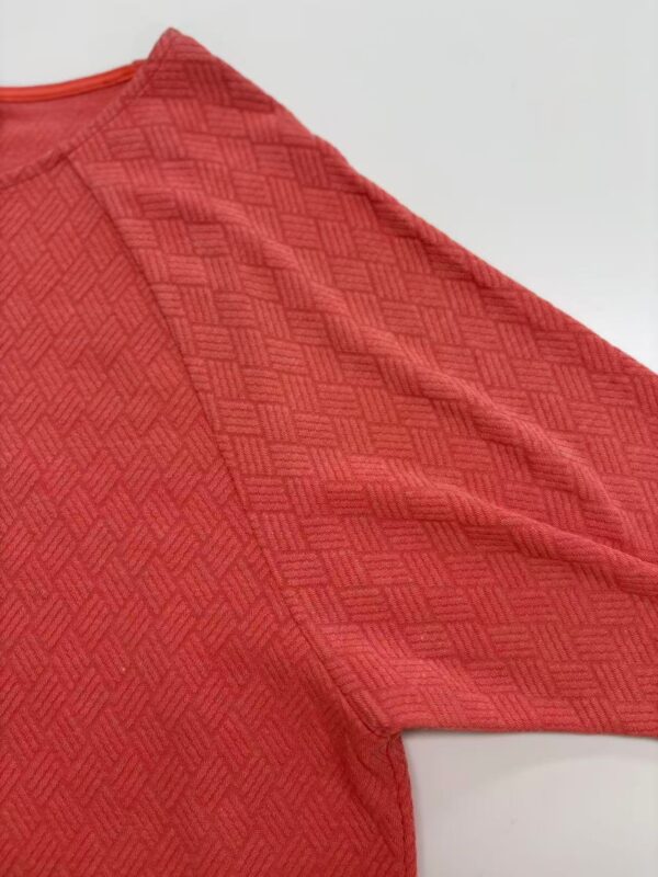 Close-up of a red men's sports jersey with textured pattern, ideal for athletic wear and active lifestyle.