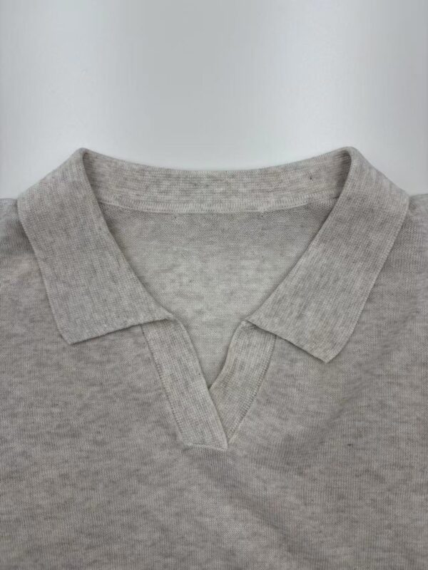Close-up of a light grey polo shirt with a V-neck collar, made from soft cotton fabric, suitable for casual and everyday wear.