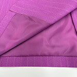 Close-up of a pink pinstripe women's suit jacket with a red button, showing detailed fabric texture and lining.